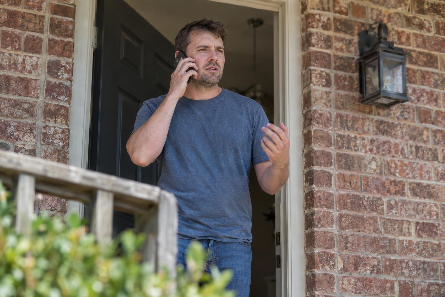 Homeowner standing in doorway of a Texas home talking on the phone